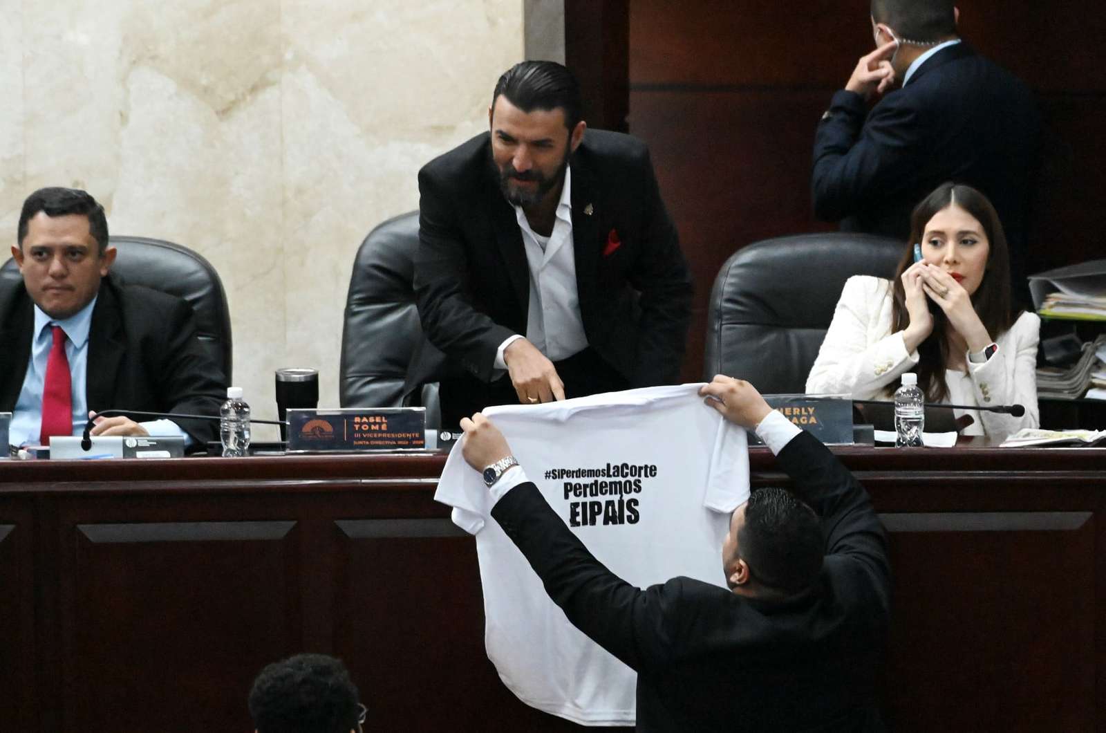 The Vice-President of the Congress, Rassel Tome, of the ruling Liberty and Refoundation (LIBRE) party, receives from a deputy of the opposition National Party, a jersey reading "If we Lose the Court, we Lose the Country" as the third attempt to elect the new judges of the Supreme Court of Justice fails, at the National Congress in Tegucigalpa, on February 11, 2023. - The Honduran Congress failed on its latest attempt to elect new Supreme Court justices due to a confrontation between deputies from the president's leftist party and the right-wing opposition. The 15 members of the highest court end their seven-year terms on February 11, but the vote to choose their successors --which began on the eve-- threatens to take several days, as both sides want the Court to respond to their interests, which is the tradition in Honduras. (Photo by Orlando SIERRA / AFP)