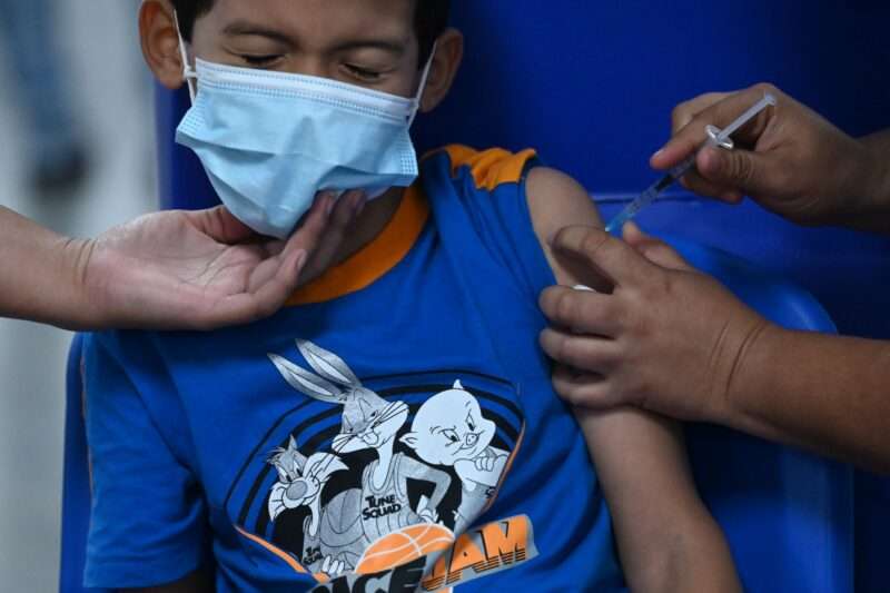 Niño salvadoreño es vacunado contra el covid-19 en un centro de salud estatal.