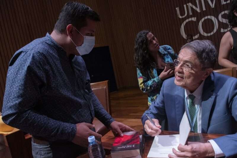 El galardonado escritor nicaragüense y exvicepresidente Sergio Ramírez (der.), firma autógrafos luego de recibir un Doctorado Honorario (honoris causa) de la Universidad de Costa Rica, en San José, el 23 de mayo de 2022. AFP