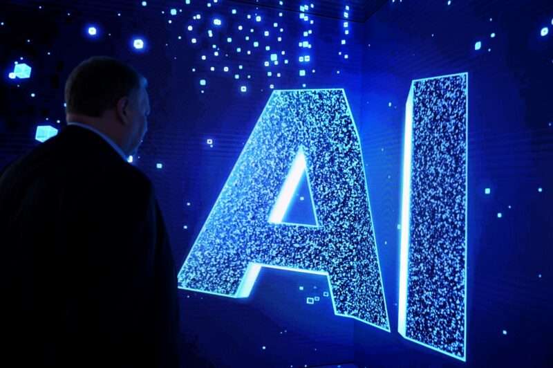A visitor watches an AI (Artificial Intelligence) sign on an animated screen at the Mobile World Congress (MWC), the telecom industry's biggest annual gathering, in Barcelona. (Photo by Josep LAGO / AFP)