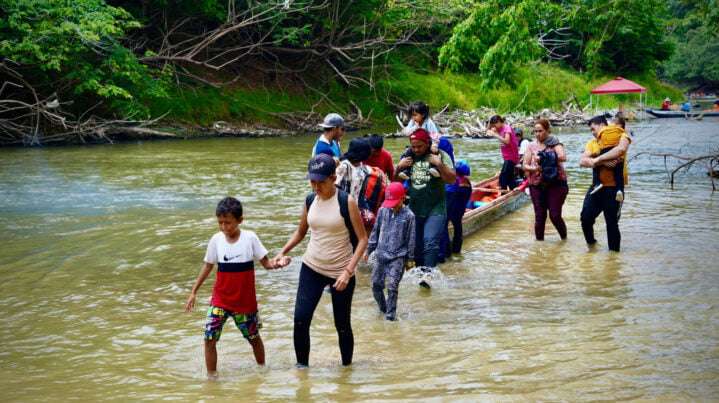 En esta imagen difundida por la OIM, migrantes pasan por la Selva del Darién con menores de edad.