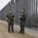 Oficiales migratorios estadounidenses junto al muro fronterizo.