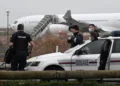 Funcionarios de aduanas de Francia vigilan el  Airbus A340 de Legend Airlines en el aeropuerto de Vatry, al este de París, donde los pasajeros indios fueron retenidos./AFP