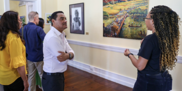 El ministro de Cultura de Belice, Francis Fonseca, escucha una explicación sobre las obras de arte.
