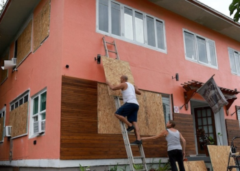 Habitantes de ciudad Belice cubren sus ventanas de vidrio con plywood para protegerse de la llegada del huracán Beryl.